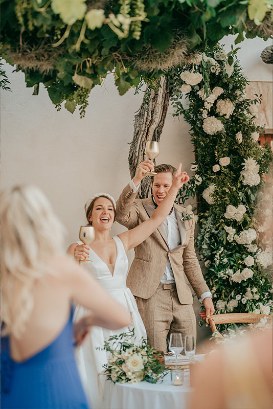 Das Hochzeitspaar freut sich gemeinsam mit ihren Gästen und stößt auf die Feierlichkeiten im Innenhof der Las Barracas Country Lodge auf Mallorca an